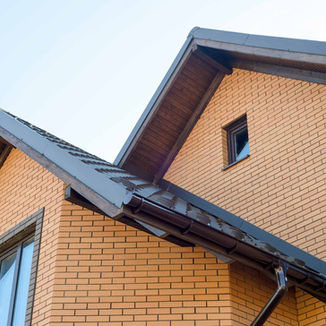 Brick house with dark brown roof and gutters