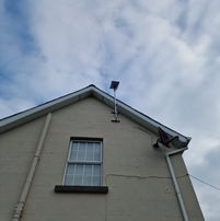 Satellite on house roof. View of the house; cloudy sky. Munster Satellite Services.