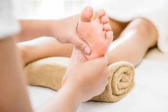 Therapist's hands massaging foot; Reflexology treatment on a massage table. D6wellness.