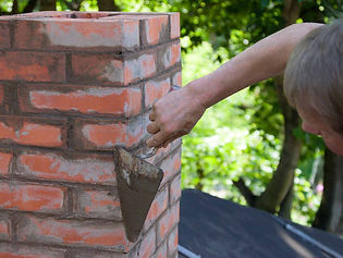 Mason repairing brick chimney with trowel