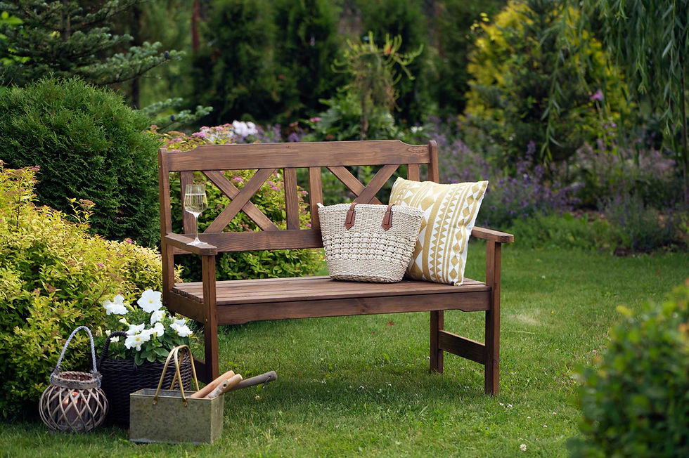 Wooden garden bench with pillow and tote bag in a lush yard