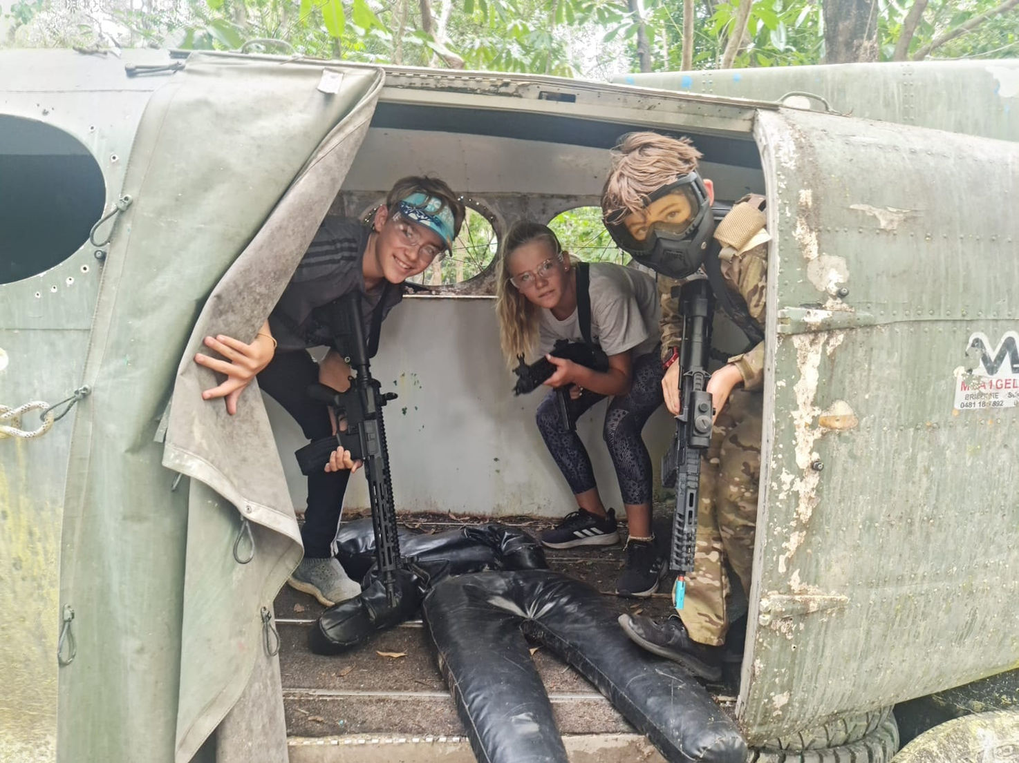 3 kids in an old aircraft carcass with their gel blasting equipment