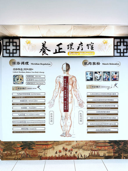 Wall display showing TCM meridian regulation and muscle relaxation services at Better Wellness