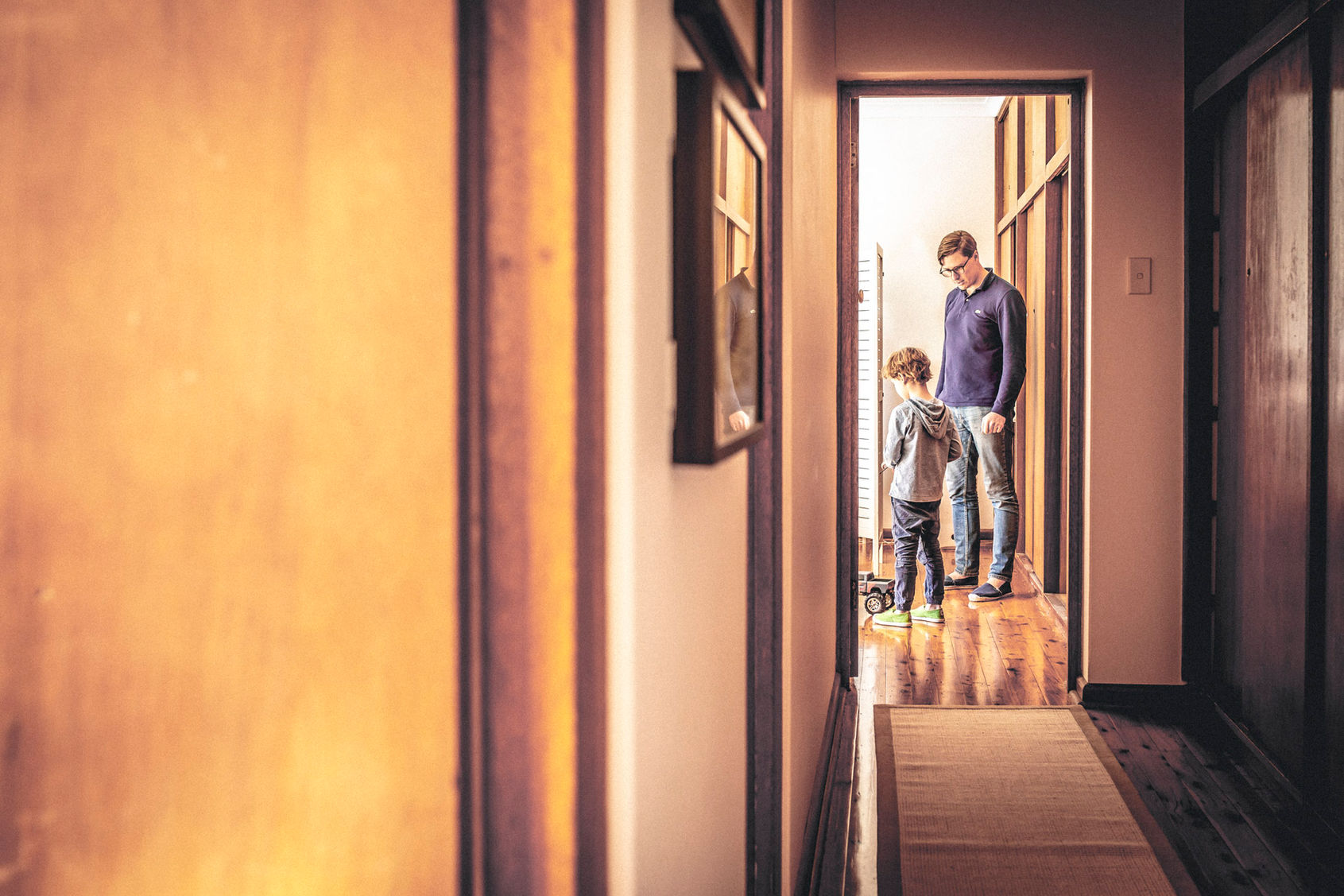 Family photography Suzanne Stevenson. Authentic phot of Dad and his son at home playing with remote control car