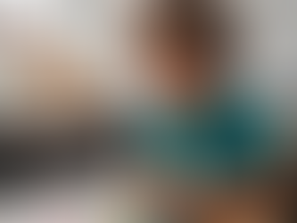 Young boy with curly hair focused on assembling a colorful puzzle at a wooden table. Bright, cozy room with potted plants on the window sill.