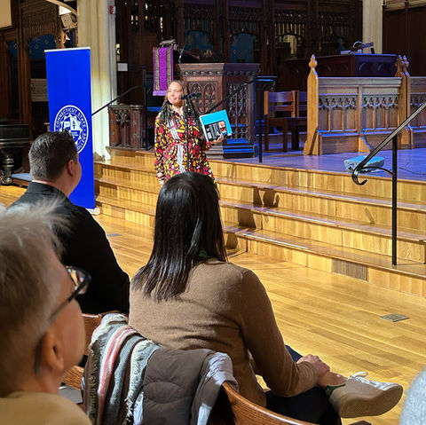 Woman talking to an audience with a smile.