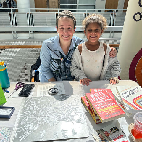 Author Ali Michael selling her books. Smiling girl stand beside her.