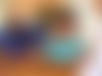 Piggy bank in focus on wooden table; smiling family of three blurred in background. Warm, cozy home atmosphere with brick wall.