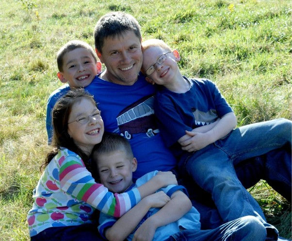 A man sitting on the grass with four children