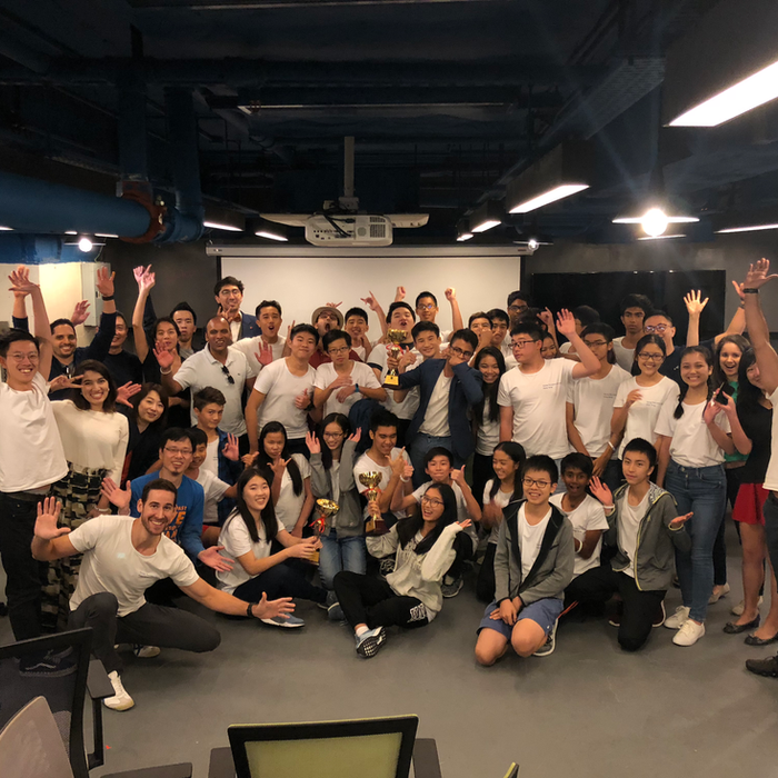 Large diverse group of young people cheering excitedly in a modern office.