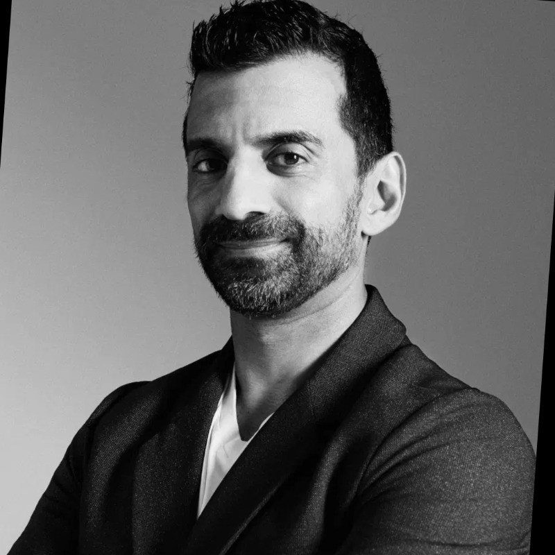 Professional black and white headshot of a smiling man with a beard.