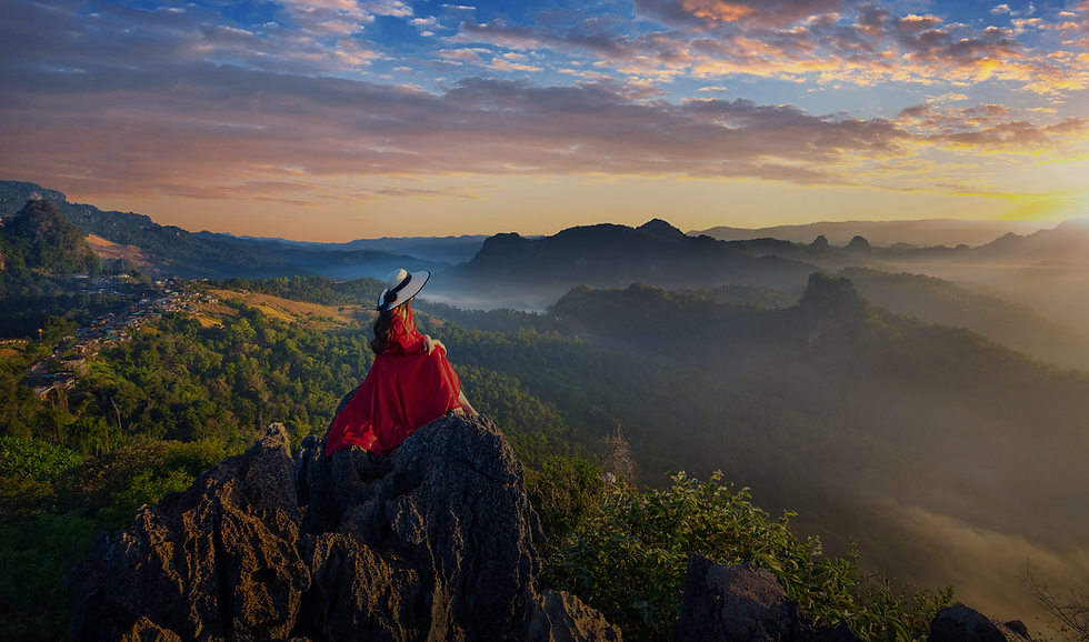 Person in red dress on mountain peak, sunrise view