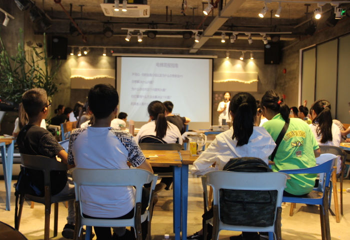 Students attending a presentation in a dimly lit room with a speaker.