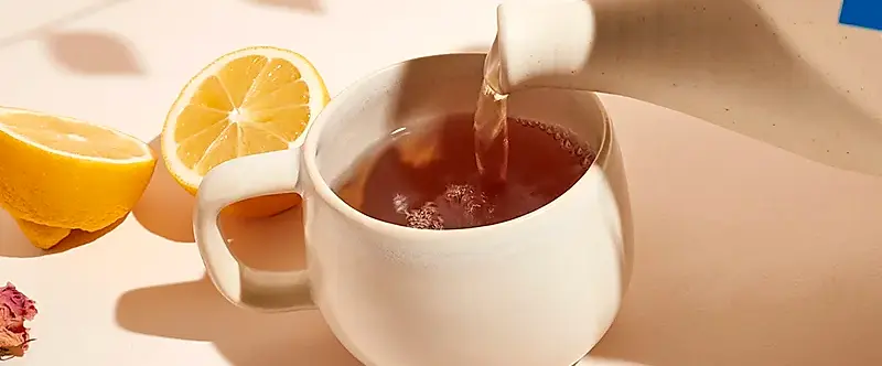A photo of tea brewed with a Dream Tea cotton sachet bags being poured into a ceramic mug.