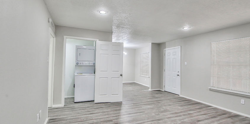 Living area with in-unit washer and dryer at Courtyards on the Park Apartments in Lubbock, TX featuring vinyl flooring and open layout.