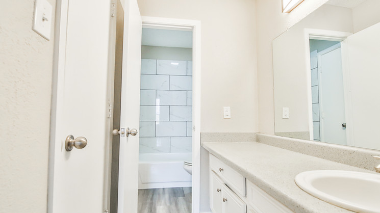 Bathroom with large vanity counter and tiled shower at Lubbock Heights Apartments in Lubbock, Texas.