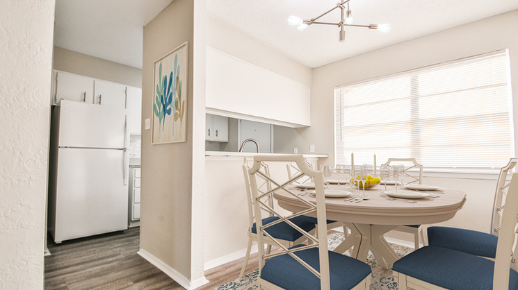 Open-concept kitchen and dining area with large window and white cabinetry at Lubbock Heights Apartments in Lubbock, TX.
