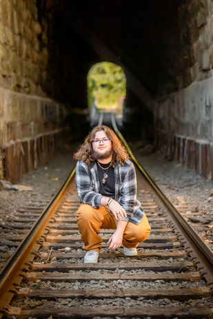 senior portrait on train tracks, train tunnel and plaid shirt