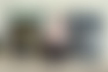 Luis Posada seated between 2 paintings