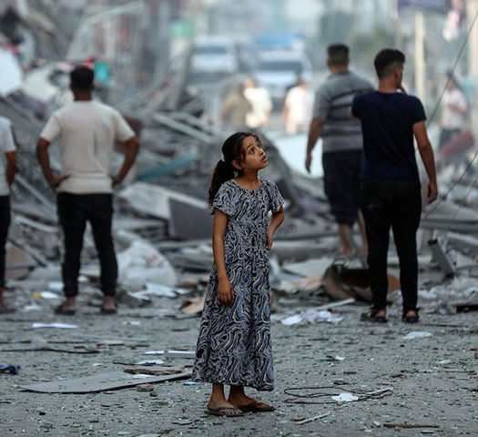 una ragazza si guarda intorno mentre è circondata da macerie di edifici distrutti a causa della guerra