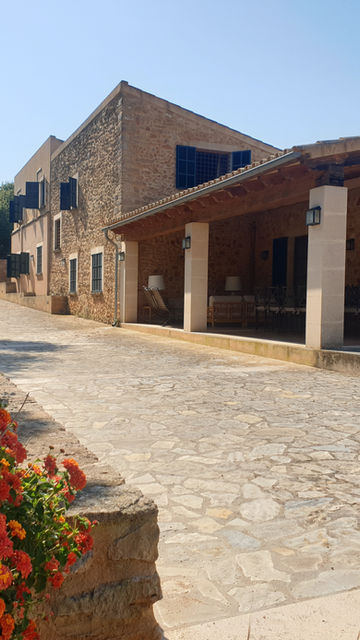 Spacious covered porch at Finca Es Rafal Pai, featuring an outdoor dining table and stunning countryside views.