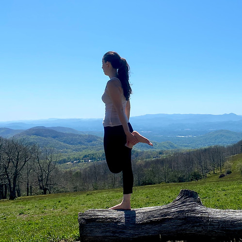 standing on a log doing a quad balance stretch to improve balance and leg mobility