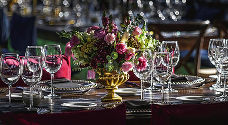 Close-up of an elegant corporate gala dinner table setup with premium glassware, floral decorations, and high-end event cater