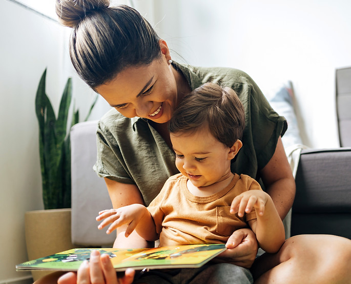 Mom reading a book with baby boy at home. Early age children education, development. Mothe