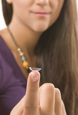A young woman holding astigmatism contacts.