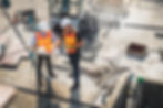Two engineer in hardhat and orange jacket posing on building site. civil engineer or archi