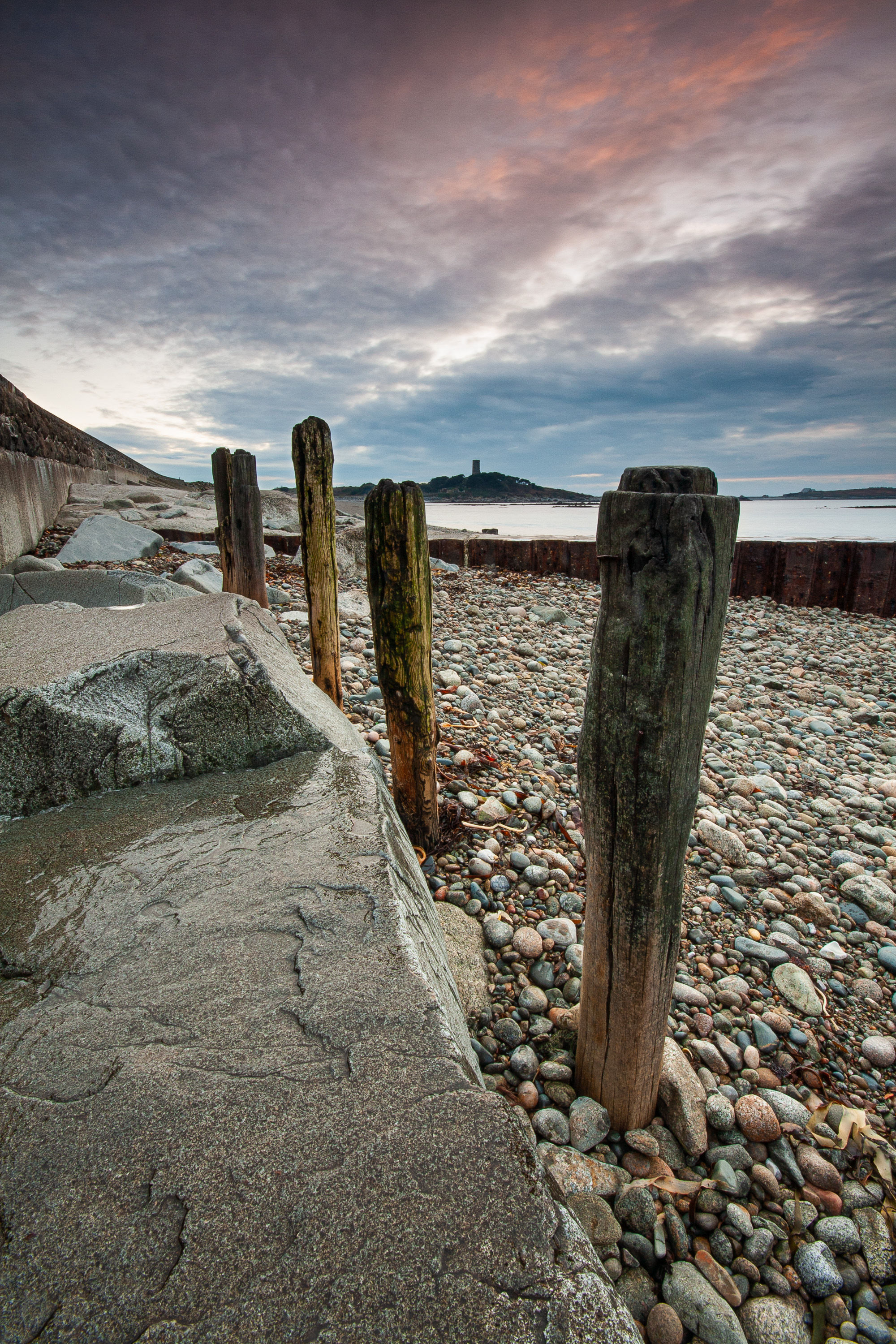 Sea defence groynes near the Shingle Bank, Guernsey with Fort Sausmarez and Lihou Island in the background