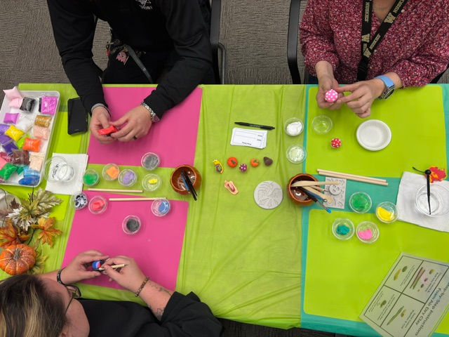 Participants at a wellness fair create autumn pumpkins, mushrooms, and snails out of air-dry clay.