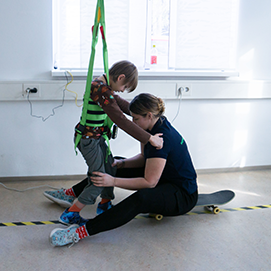 Ein Kind in der Physiotherapie mit Sicherheitsgurten zur Unterstützung beim Gehen