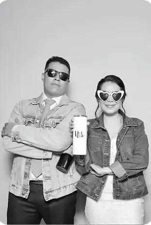 Man and woman in denim jackets and sunglasses in a photo booth