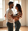 A couple smiling warmly while learning a dance step in a bright, private studio._edited.jp