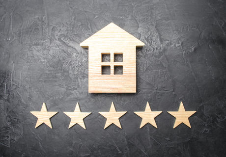 Wooden house and five stars on a gray ba