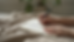 Eye-level view of a person writing slowly in a journal on a soft blanket.