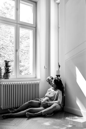 Black and white portrait of an expecting couple holding hands and embracing during an intimate maternity session