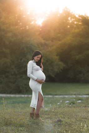 Schwangere Frau bei einem Schwangerschaftsfotoshooting im Sonnenuntergang.