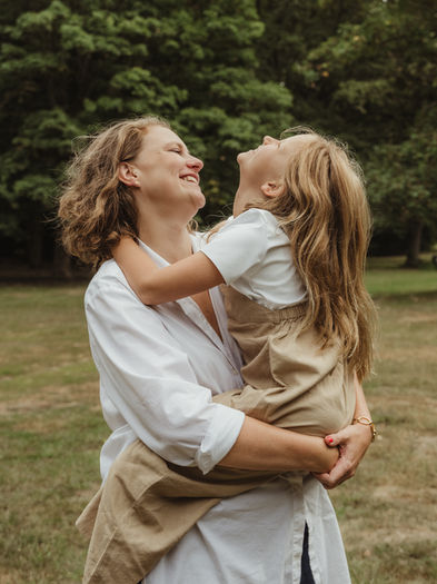 Family photoshoot in the park, Mother and daughter hugging. Both laughing.