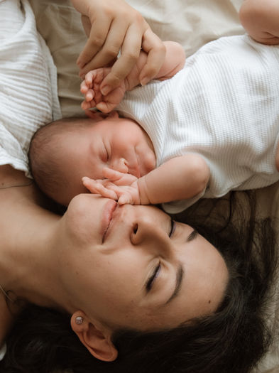 Peaceful newborn snuggled in his mothers arms, captured in a warm in-home family photoshoot.