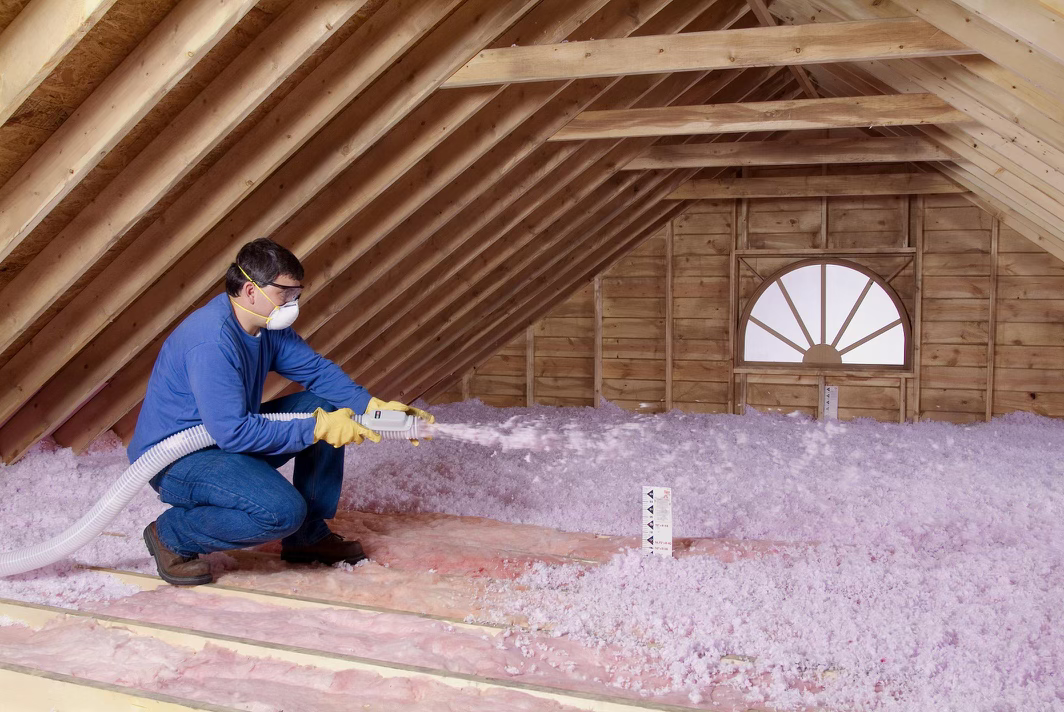 Blown-in fibreglass insulation being installed across an attic