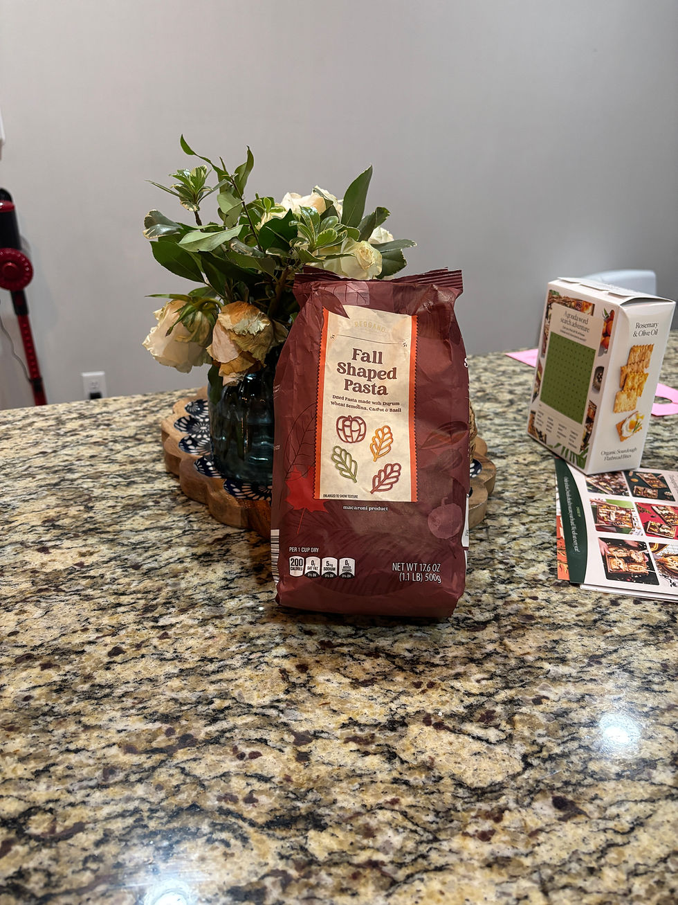 Bag of pasta on a counter leaning on flowers in a vase