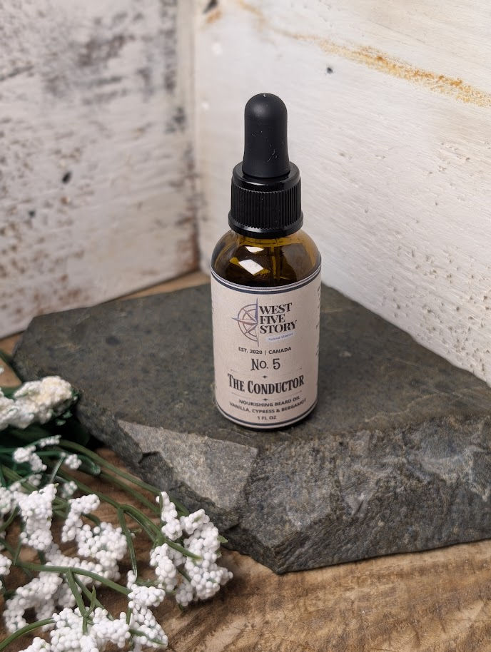 Thumbnail: A professional product photograph of a 1 fl oz amber glass dropper bottle of No. 5 The Conductor Nourishing Beard Oil. The bo