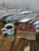 Thumbnail: “A white mug with the letter P sits beside a stack of three vintage books with eyeglasses on top, arranged on a weathered woo