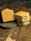 Thumbnail: Handcrafted Bee’s Knees soap bars in soft golden tones, with one bar standing on a stone base and two stacked beside it, disp
