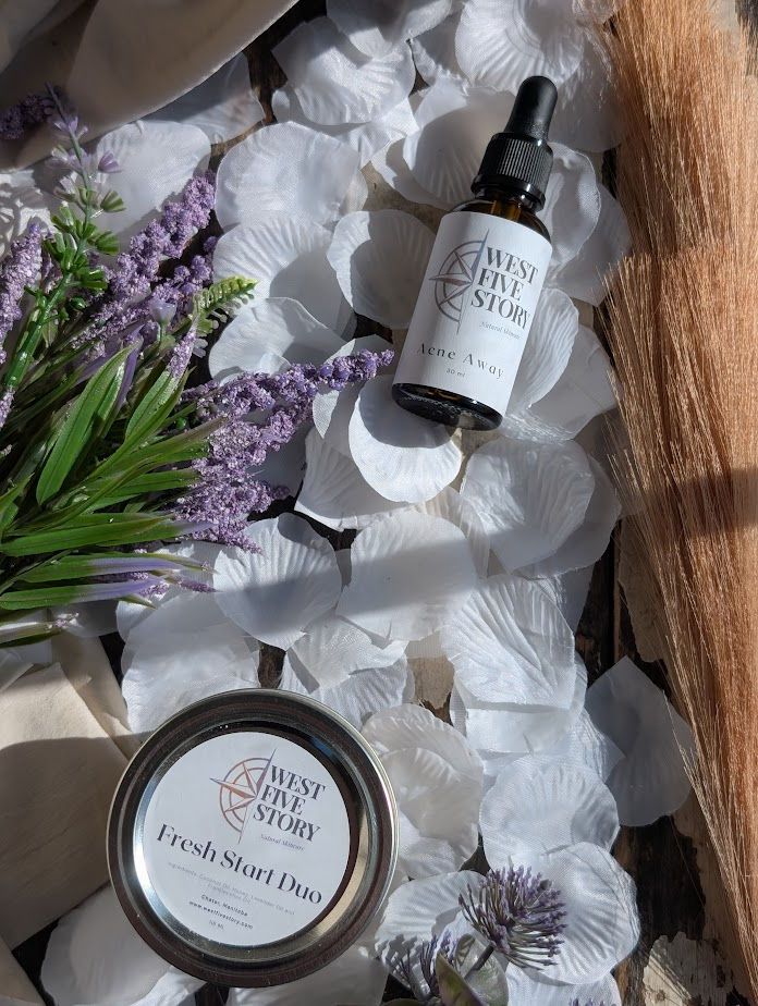 West Five Story Fresh Start Duo balm tin and Acne Away facial serum dropper bottle arranged on white rose petals with lavende