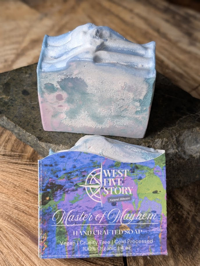 A lifestyle product photograph of West Five Story Master of Mayhem Handcrafted Natural Soap. One bar is displayed upright on