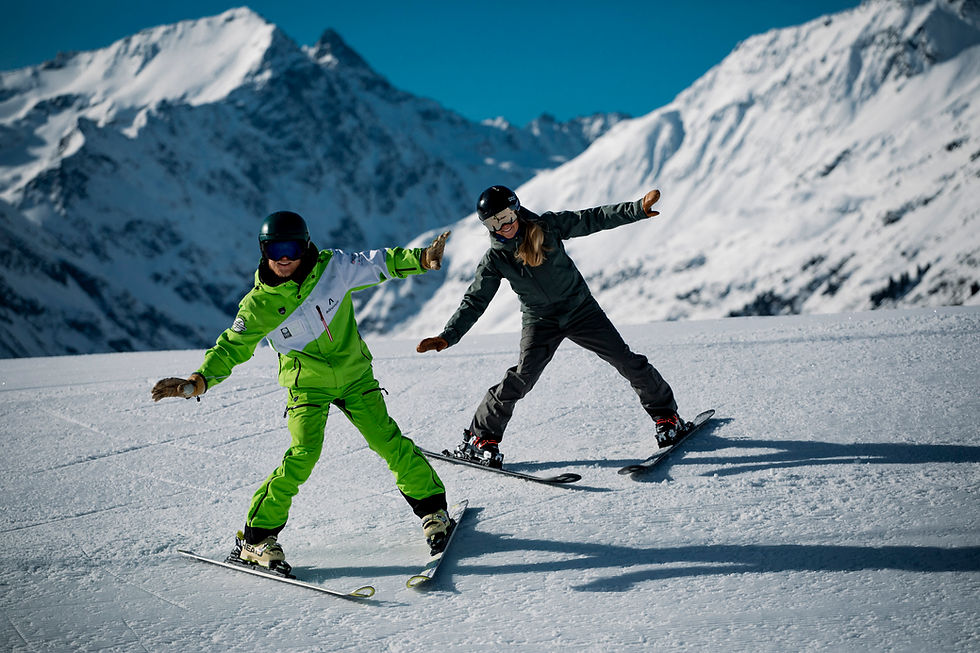 Zwei Skifahrer gleiten auf Schnee mit verschneiten Bergen im Hintergrund.