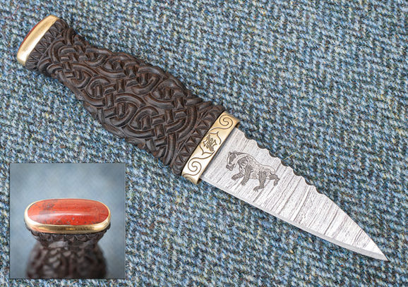 Traditional Scottish Sgian Dubh with Bog Oak handle carved with Celtic Knotwork. Fife Red Jasper pommel stone and brass fittings. Lower ferrule custom engraved with letter Z and Celtic Knotwork. Patterned steel blade engraved with custom badger design. Brown leather sheath embossed with Lion Rampant.